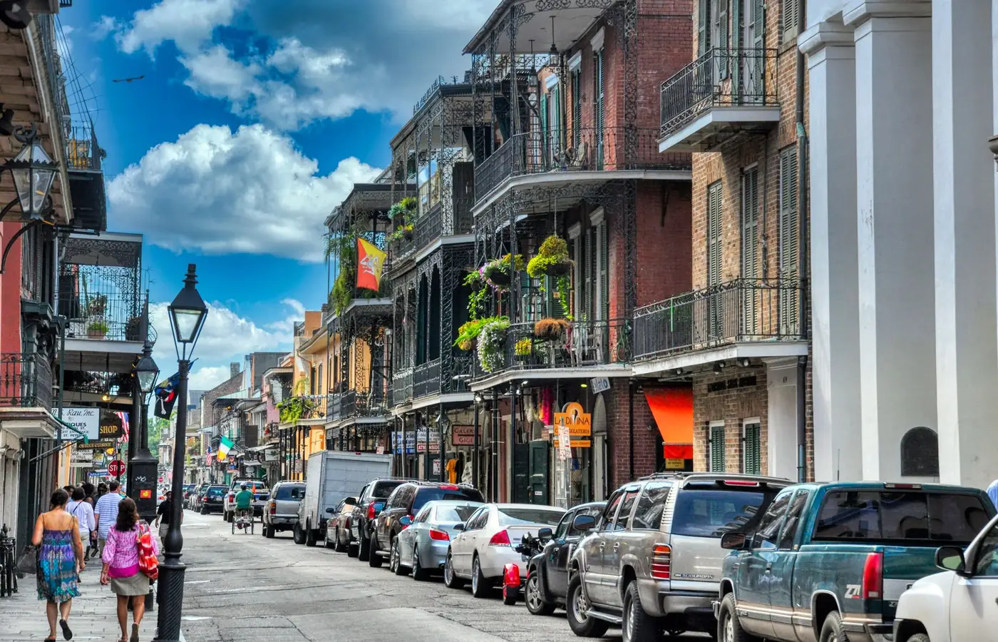 A New Orleans street of balconied buildings with people walking — a stock photograph of the city this practice is set in.